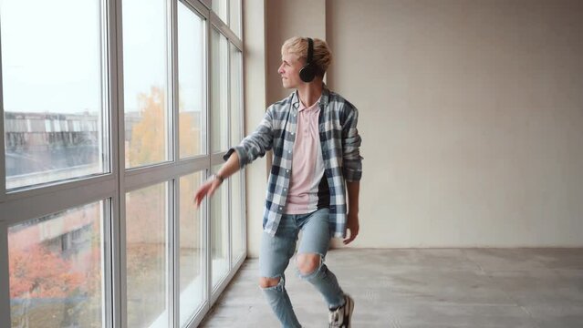Young man dancer in casual dancing in front of wall. People emotions lifestyle concept. Mock up copy space.