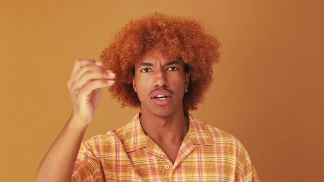 Guy looking at the camera is outraged and strongly disagrees, isolated on brown background in studio