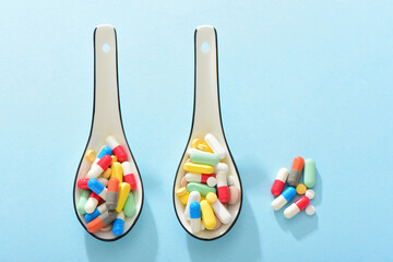 Medicine on a blue background and two ceramic spoons filled with medicine