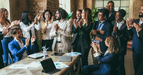 Multigenerational colleagues clapping hands for a succesful green energy project inside business modern office - Teamwork greeting each others for environmental deal - Soft focus on center woman face - obrazy, fototapety, plakaty