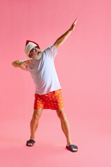 Full size portrait of Santa Claus dressed colorful pajama doing morning exercises for arms,...