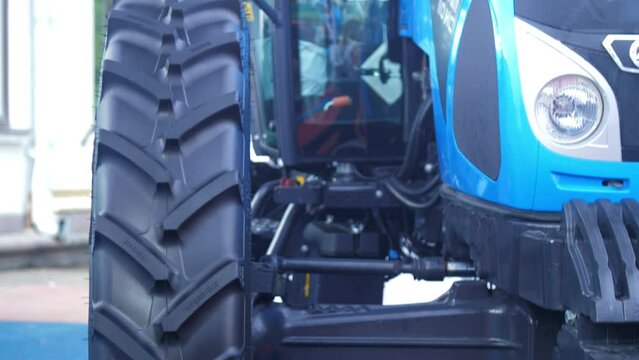 Blue tractor with large wheels stands on farm yard extreme closeup. Preparation for sowing works. New technology for farmers comfort
