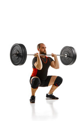 Focused bearded man, athlete with strong body training, lifting heavy weights, barbell against white background