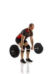 Bearded, muscular, young man, weightlifter training, doing exercise of deadlift with barbell...