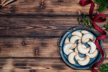 Homemade vanilla biscuits on a metal tray on a wooden background with a red natural ribbon and fir branches. Banner Background. Top view.