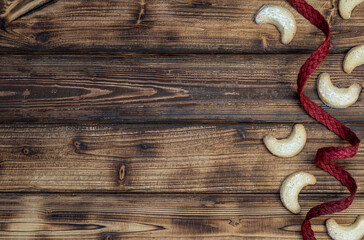 Traditional Christmas background. Homemade vanilla cookies and red natural ribbon on rustic wooden background. Top view. Christmas banner. 
