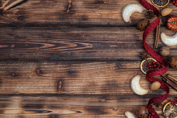 Traditional Christmas background. Homemade vanilla candy, nuts, Christmas spices, dried oranges, cinnamon and red natural ribbon on a rustic wooden background. Top view. Christmas banner.