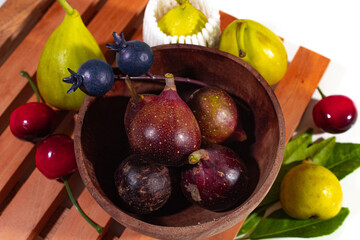 various colored models of figs, served on a wooden coaster with a mini wooden bowl
