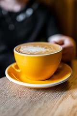 Woman hand holding cup of hot coffee latte cappuccino sit in cafe
