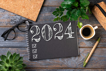 New year resolutions 2024 on desk. 2024 resolutions list with notebook, coffee cup on table. Goals,...