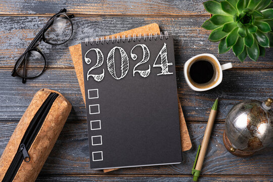 New year resolutions 2024 on desk. 2024 resolutions list with notebook, coffee cup on table. Goals, resolutions, plan, action, checklist concept. New Year 2024 template, copy space