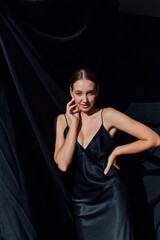 Beautiful fashionable slender woman in black silk evening dress