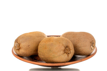 Three ripe sweet kiwis on a clay plate, macro, isolated on white background.