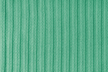Obraz premium Jersey textile background , green striped knitted fabric. Woolen knitwear, sweater, pullover surface texture, textile structure, cloth surface, weaving of knitwear material. Wallpaper, backdrop.