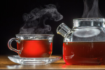 Tea pot and cup of tea on wooden table. Closeup.