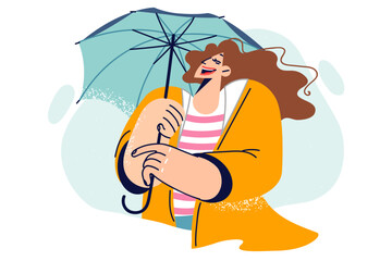 Happy woman with umbrella laughs while walking, enjoying fresh air and warm autumn weather