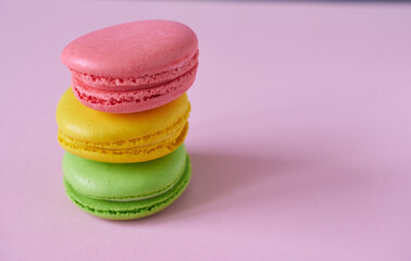 Multicolored macaroons on a pink background. Beautiful background of cookies.