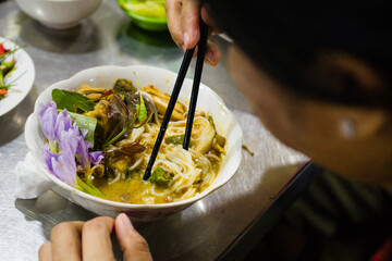 Woman eating noodles in the local orussey market in Phnom Penh