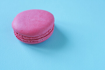 Pink macaroon on blue background. Copy space for text.