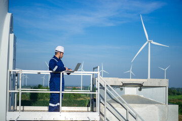 A maintenance engineer is checking the operation of a wind turbine with his laptop.