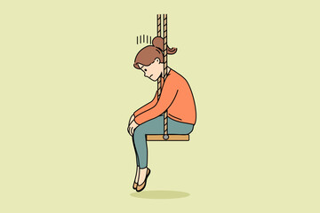 Upset little girl sits on swing with head down after parents divorce or reprimand at school. Upset schoolgirl is sad because of problems with friends who do not want to go out together