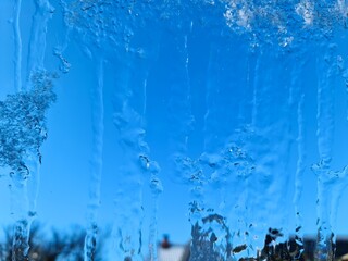 Frozen ice on a window with a blue sky background.
