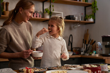 Mother and daughter eating homemade gingerbreads with chocolate