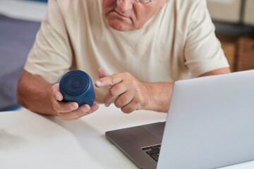 Senior man figuring out how to turn on portable speaker