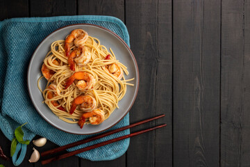 Red pork noodles with barbecue pork, crispy pork, dumplings, green vegetables, healthy food, Thai, Chinese, Hong Kong, arranged on a black wooden table. Top view with text copy space.