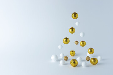 Christmas tree made of gold and white decoration on white background. Minimal Christmas or New Year concept.