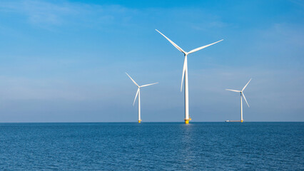 Windmill farm in the ocean Westermeerwind park, windmills isolated at sea on a beautiful bright day in the Netherlands Flevoland Noordoostpolder. Huge windmill turbines at sea - obrazy, fototapety, plakaty