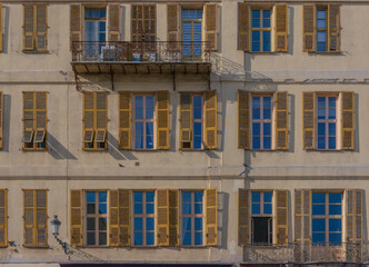 Old-rendered French apartment building with coloured window shutters and balconies - 685106505