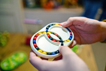 Children's hands holding a puzzle with two circles of colorful balls