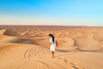 Dubai desert sand dunes, Asian woman on Dubai desert safari, United Arab Emirates vacation, woman vacation in Dubai walking in the sand dunes of Dubai - obrazy, fototapety, plakaty