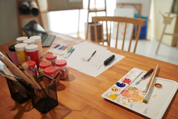 Plastic palette, paints and felt tip pens on desk in studio