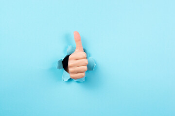 Thumb up,  positive hand gesture, approval or agreement, optimism and emotion, blue torn paper