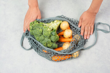 Mesh bag with vegetables, shopping grocery, healthy food ingredients, potato, broccoli and carrots, zero waste
