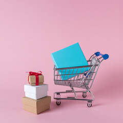 Gift boxes in shopping cart on pink background. Minimal sale con