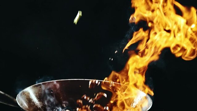 Udon beef. Stir-fry noodles. Che cooking delicious wok, frying ingredients inside wok pan with fire flames against black background. Concept of Asian food, cuisine, restaurant, taste, cooking, recipe