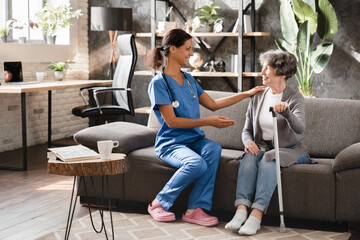 Nurse caregiver doctor giving advice to elderly senior woman, prescribing treatment at home. Hospice elderly care. Geriatrics concept. Disabled patient