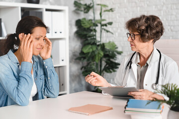 Mature female woman patient suffering complaining about headache migraine menopause, rubbing her...