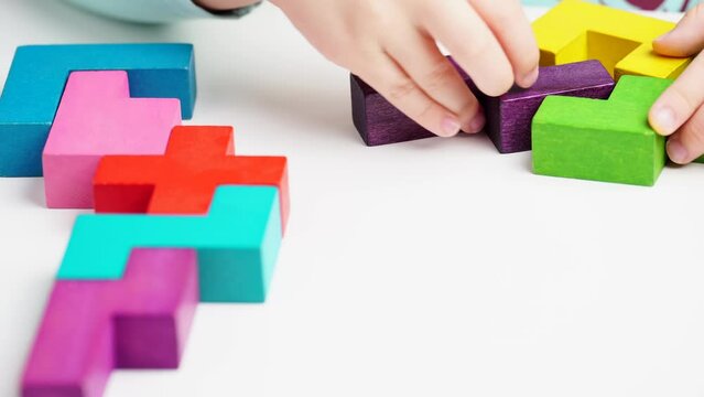 Girl play with colorful wooden blocks on table, close up. Children education game. Concept of logical thinking.