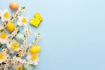 Festive background with spring flowers and naturally colored eggs and Easter bunnies, white...