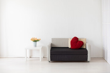 a sofa with heart-shaped pillows a table with flowers in a bright room
