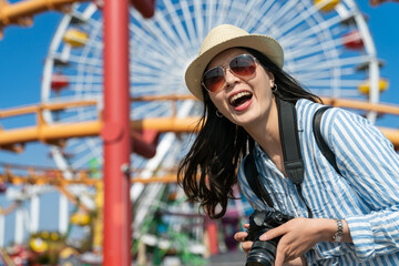 closeup portrait of happy stylish asian taiwanese woman photographer enjoying holiday in amusement park on Ferris Wheel backdrop at santa monica pier