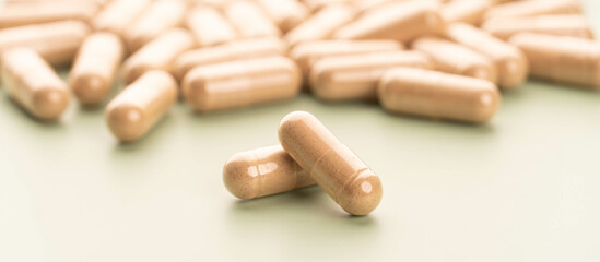 Close up of alternative medicine herbal capsules on green background. Natural herbs and homeopathic supplement product for healthy good life.