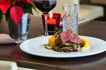 Close up Gourmet tasty roast beef steak with mashed potatoes and other vegetables on a white plate, served food in a restaurant, wine