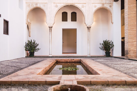 Exterior of ancient Horno del Oro house in Granada Spain with small pool with fountain in center of patio