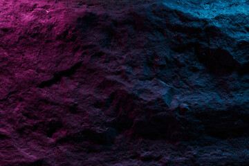Black stone texture in pink blue neon lighting, dark abstract background. Natural mineral rock close up details, empty backdrop with copy space for design