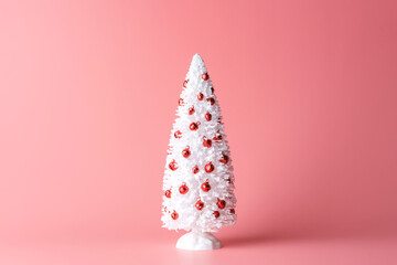 Minimal composition of white Christmas tree on pastel pink background. New Year concept.